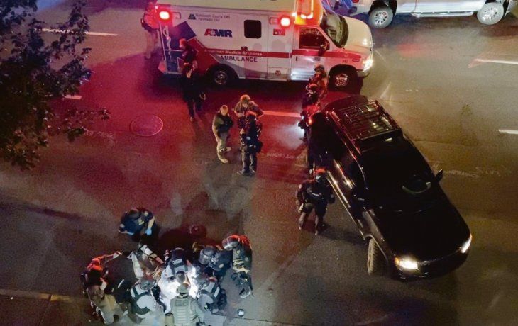 DESCONTROL. Médicos y policías asistieron en plena calle a una víctima de disparos en Portland, estado de Oregon, en la noche del sábado.